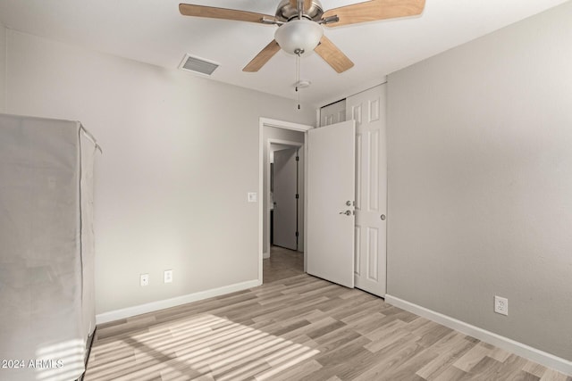 unfurnished bedroom featuring ceiling fan, light hardwood / wood-style floors, and a closet