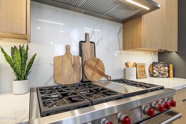 kitchen with light brown cabinets, high end stainless steel range oven, tasteful backsplash, custom range hood, and light stone counters