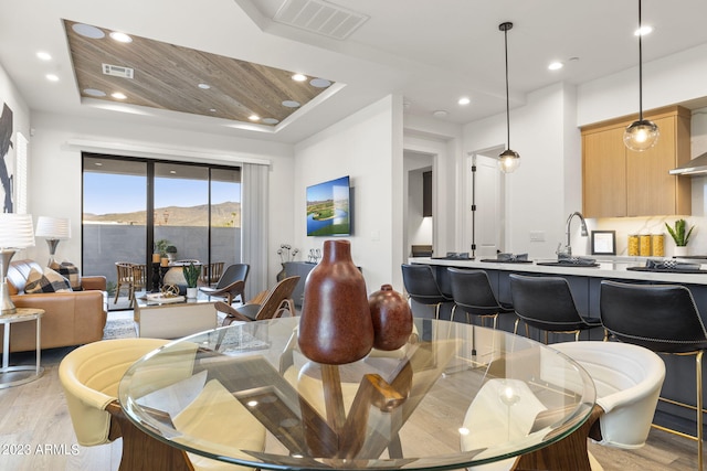 dining space featuring sink, light hardwood / wood-style floors, and wooden ceiling