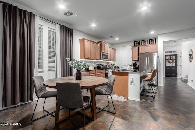 kitchen featuring appliances with stainless steel finishes, light brown cabinetry, sink, and a kitchen breakfast bar