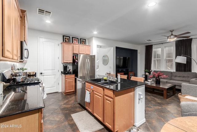 kitchen with a kitchen island, stainless steel appliances, ceiling fan, dark stone counters, and sink