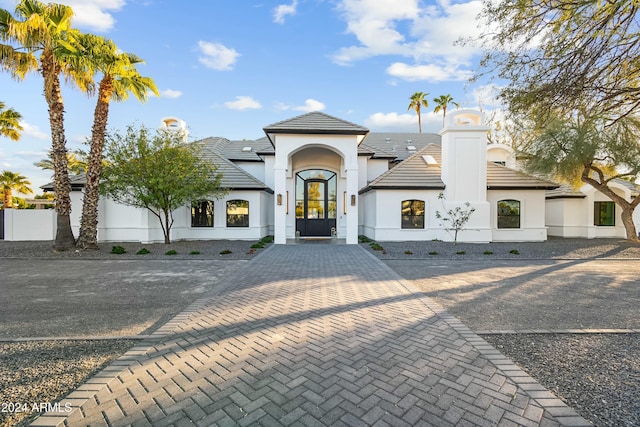 view of front of home with a tiled roof, fence, and stucco siding