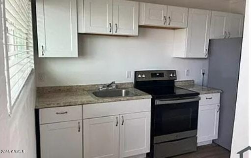 kitchen with sink, white cabinets, and electric stove