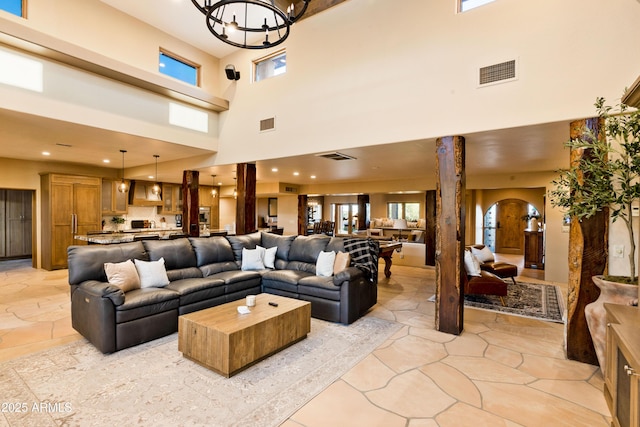 living area with arched walkways, a wealth of natural light, visible vents, and an inviting chandelier