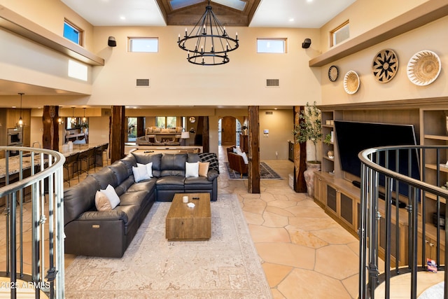 living area featuring a high ceiling, visible vents, and an inviting chandelier