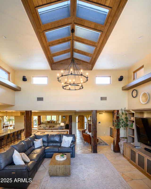 living room featuring a chandelier, plenty of natural light, and a towering ceiling