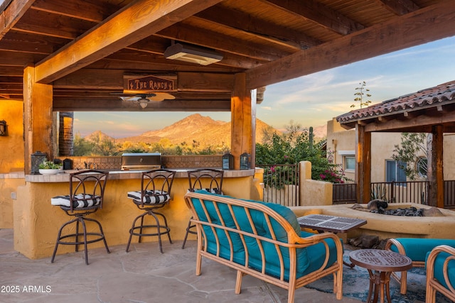 view of patio featuring outdoor wet bar, area for grilling, fence, a gazebo, and a mountain view