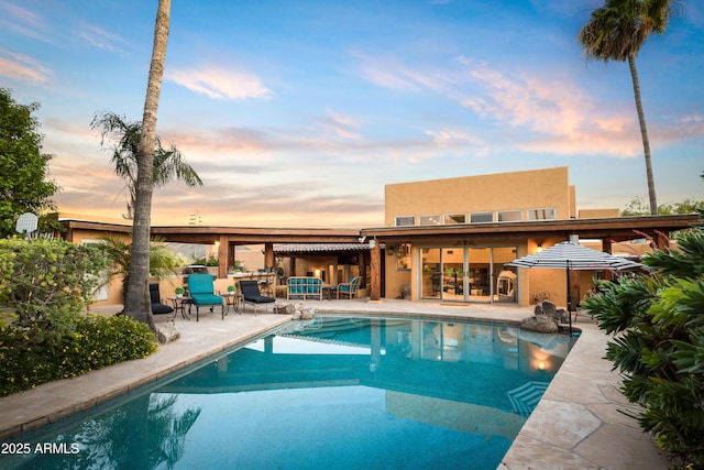 pool at dusk featuring a patio area and an outdoor pool