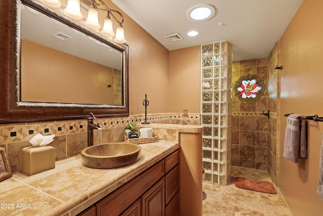 full bath featuring visible vents, vanity, and walk in shower