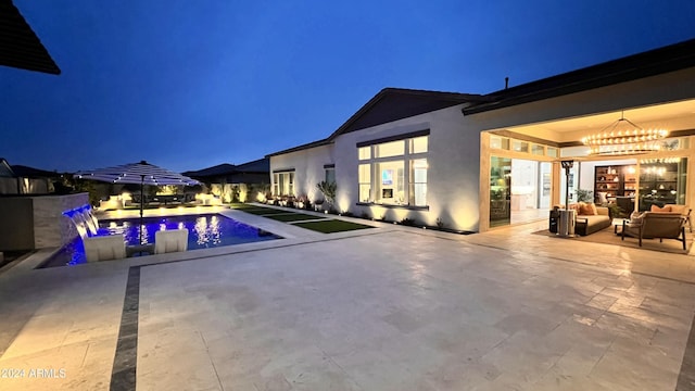 pool at twilight with outdoor lounge area and a patio