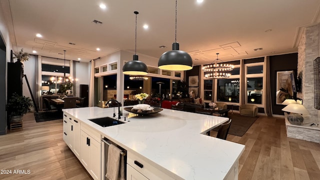 kitchen featuring light stone counters, a center island with sink, white cabinetry, and sink