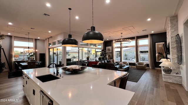 kitchen featuring a large island, sink, hanging light fixtures, light hardwood / wood-style flooring, and white cabinets