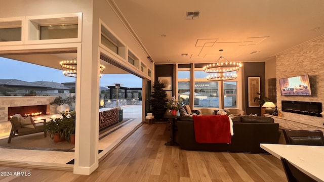 interior space with a wealth of natural light, an inviting chandelier, ornamental molding, and hardwood / wood-style flooring