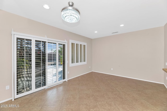 unfurnished room featuring a chandelier and light tile patterned floors