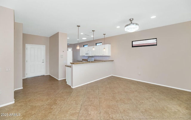 kitchen featuring white cabinetry, kitchen peninsula, and hanging light fixtures