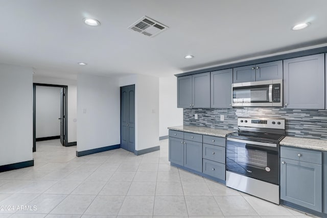 kitchen featuring tasteful backsplash, light stone counters, light tile patterned floors, and stainless steel appliances