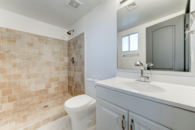 bathroom featuring a tile shower, tile patterned flooring, vanity, and toilet