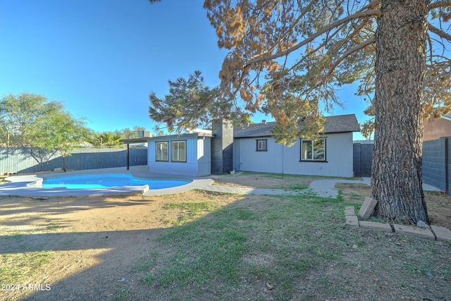 rear view of property featuring a lawn and a fenced in pool