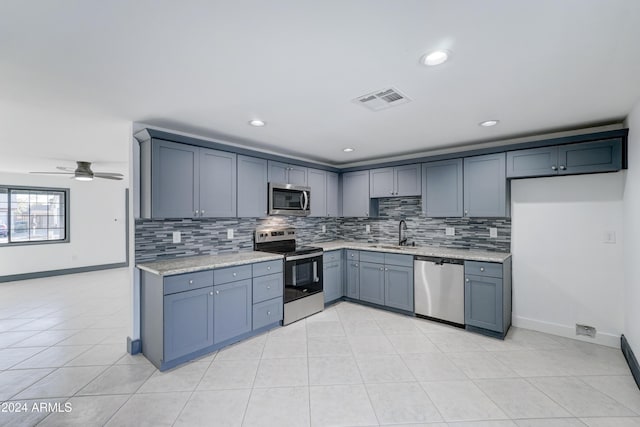 kitchen with appliances with stainless steel finishes, backsplash, ceiling fan, sink, and light tile patterned flooring