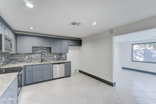 kitchen with light stone countertops, appliances with stainless steel finishes, backsplash, gray cabinetry, and sink