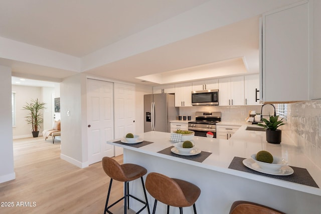 1301 N 44th St, Phoenix, AZ 85008 - kitchen featuring stainless steel appliances, a sink, a peninsula, decorative backsplash, and baseboards