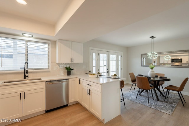 1301 N 44th St, Phoenix, AZ 85008 - kitchen with appliances with stainless steel finishes, a sink, white cabinetry, decorative backsplash, and light wood-type flooring