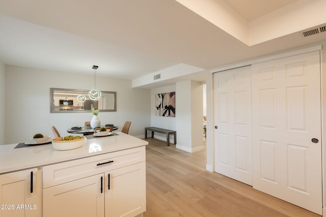 1301 N 44th St, Phoenix, AZ 85008 - kitchen featuring light wood-type flooring, pendant lighting, light countertops, white cabinets, and baseboards