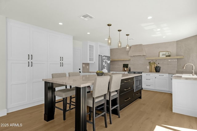 10013 N 106th Pl, Scottsdale, AZ 85258 - kitchen featuring a kitchen island, light wood-style flooring, appliances with stainless steel finishes, white cabinetry, and wall chimney exhaust hood