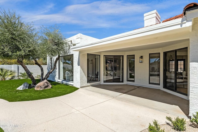 10013 N 106th Pl, Scottsdale, AZ 85258 - entrance to property featuring stucco siding, a lawn, a chimney, and a patio area