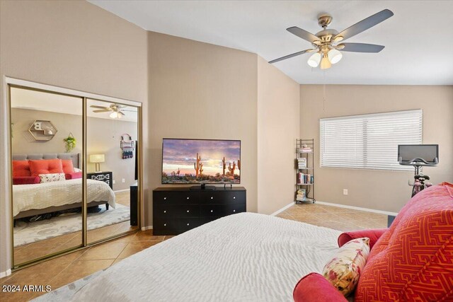 bedroom featuring lofted ceiling, light tile patterned floors, a closet, and ceiling fan