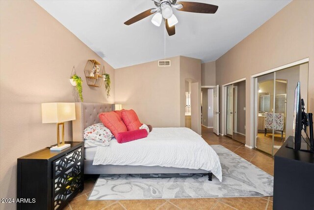 tiled bedroom with multiple closets, lofted ceiling, and ceiling fan