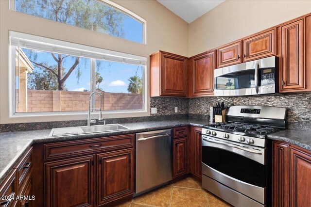 kitchen with backsplash, appliances with stainless steel finishes, sink, and light tile patterned floors