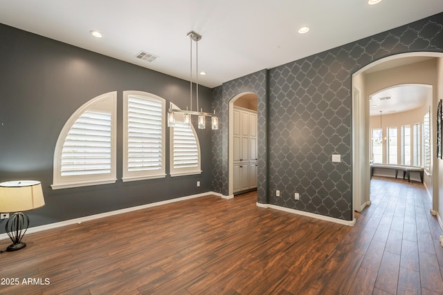 18283 N 93rd St, Scottsdale, AZ 85255 - empty room with an accent wall, wallpapered walls, baseboards, arched walkways, and dark wood-type flooring