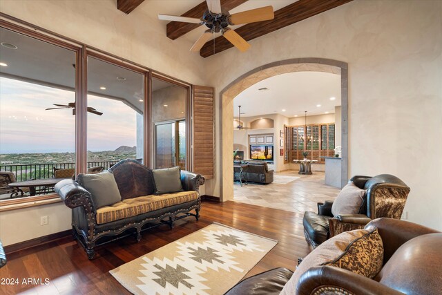 living room featuring ceiling fan, wood-type flooring, and beamed ceiling