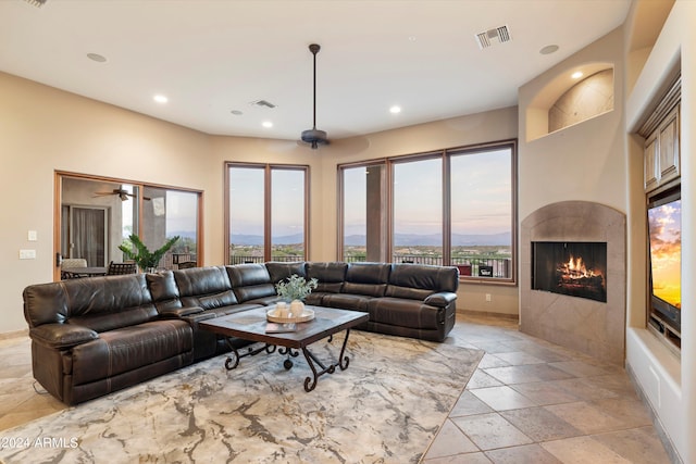 living room with ceiling fan, a tiled fireplace, and a mountain view