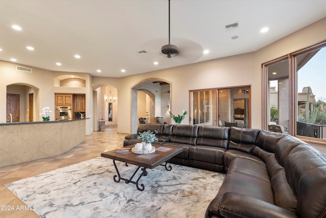 living room with ceiling fan with notable chandelier, sink, and light tile patterned floors