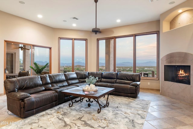 living room featuring ceiling fan, a mountain view, and a tiled fireplace