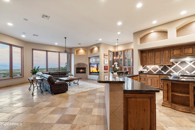 kitchen featuring sink, tasteful backsplash, a spacious island, and decorative light fixtures