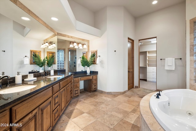 bathroom with a chandelier, a relaxing tiled tub, and vanity