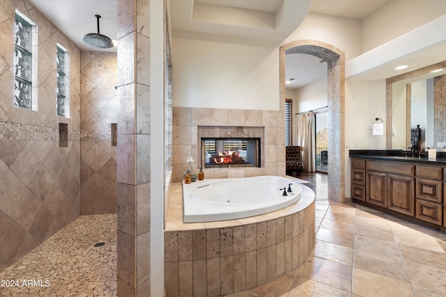 bathroom featuring a tile fireplace, separate shower and tub, and vanity