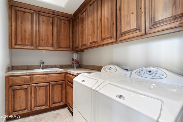 laundry area with cabinets, sink, light tile patterned floors, and separate washer and dryer