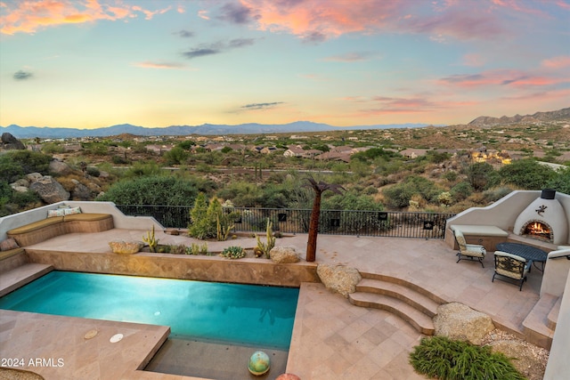 pool at dusk with a mountain view and a patio area