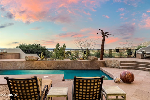 pool at dusk featuring a patio