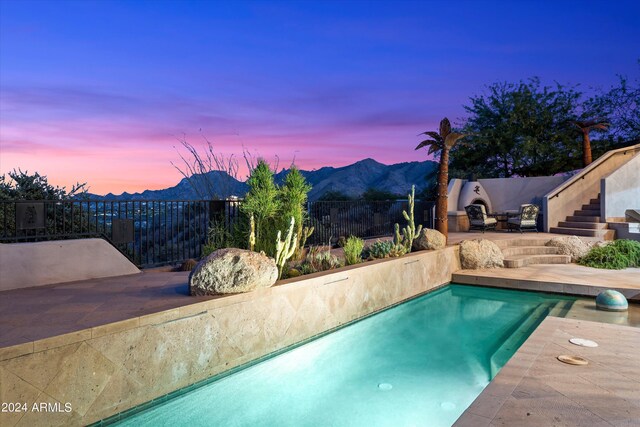 pool at dusk with a mountain view and a patio area