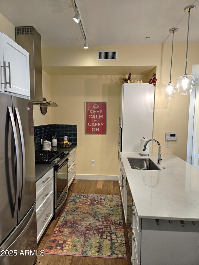 kitchen with visible vents, dark wood-type flooring, a sink, stainless steel appliances, and wall chimney exhaust hood