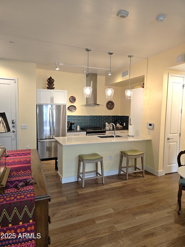 kitchen with visible vents, a breakfast bar, backsplash, stainless steel appliances, and wall chimney exhaust hood