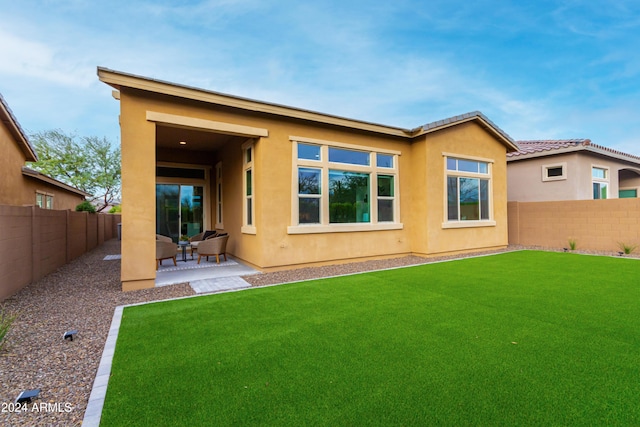 rear view of property featuring a lawn and a patio