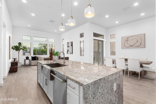 kitchen with dishwasher, pendant lighting, a kitchen island with sink, and sink