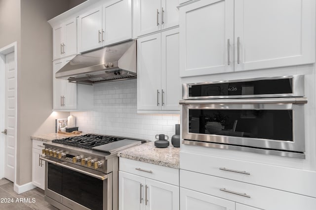 kitchen featuring white cabinets, decorative backsplash, light stone countertops, and stainless steel appliances