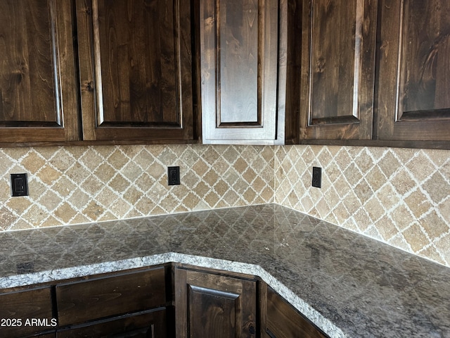 kitchen with decorative backsplash, dark brown cabinetry, and dark stone counters